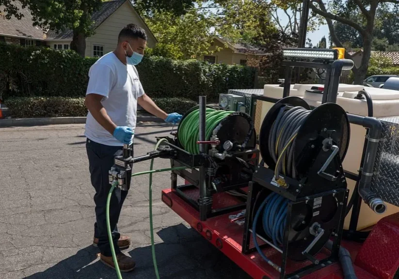 Man operating hose reels on trailer.